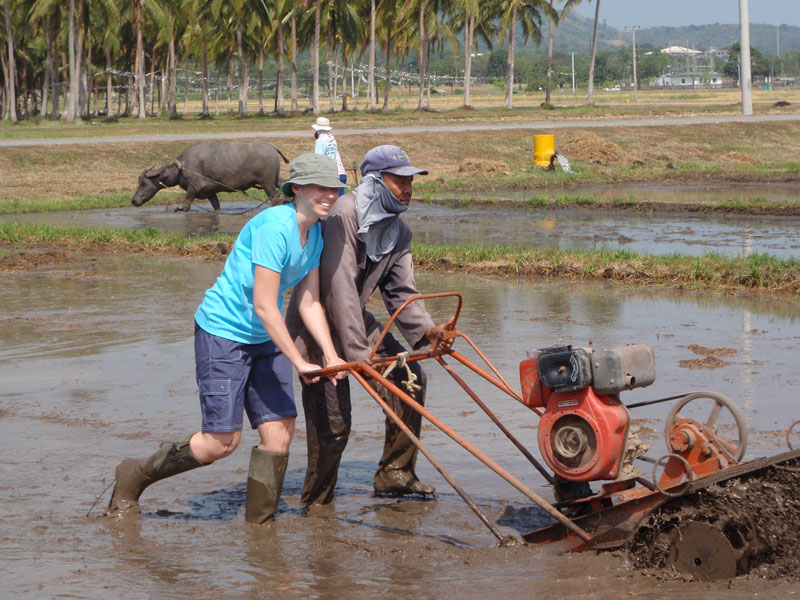 two people pushing a piece of equipment through a muddy, shim deep, pool of water.