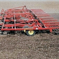 Tillage equipment, with several rows of pointed shanks, in a field.