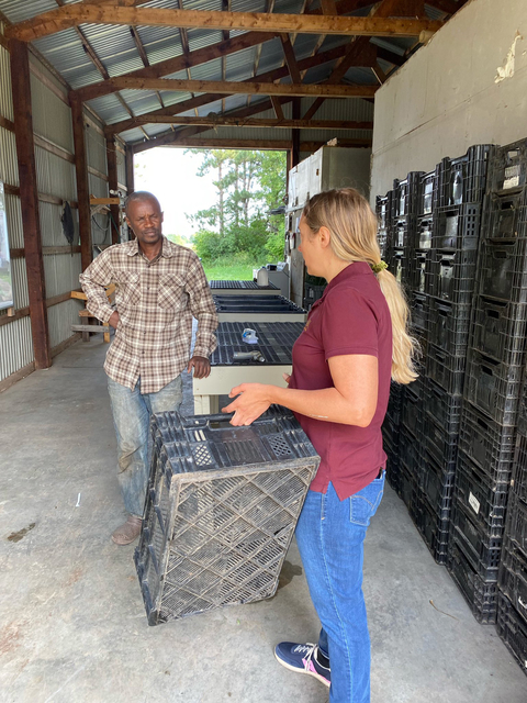 Extension educator holding a crate and talking to a farmer.