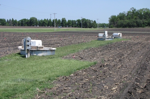 plowed soil with patch of grass where water drainage equipment is located.