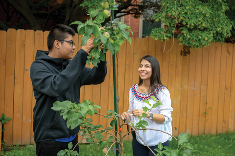 Master Gardener intern and teen with apple tree