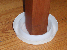 a white plastic dish within a dish under a furniture leg