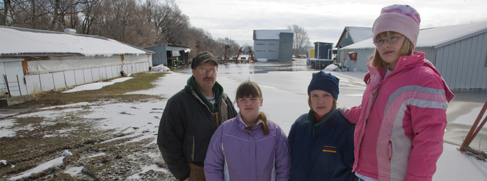Family of four with snowy farm in the background