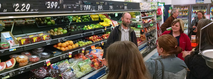 Ryan Pesch standing in front of a rural grocery store produce cooling talking to class attendees about proper produce handling.