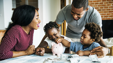Family at a table placing money in a bank