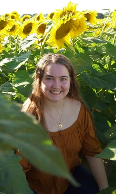 4-H'er Ella L. posing for photo in sunflower field