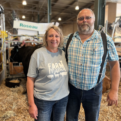 A woman and a man standing in a beef cattle stall at the state fair. 
