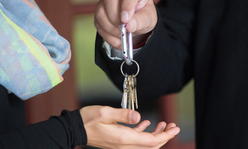 A business owner handing over keys to their business to a new owner.
