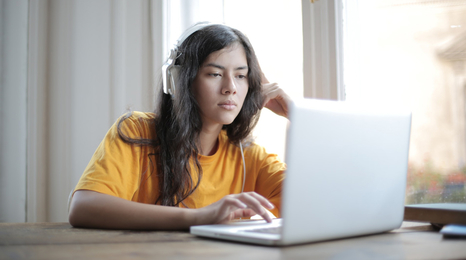 A young person wearing headphones listening to a podcast