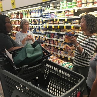 Three women in the cheese aisle at a grocery store.