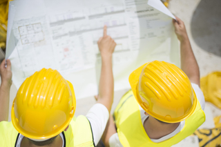Engineers reviewing a construction site blueprint